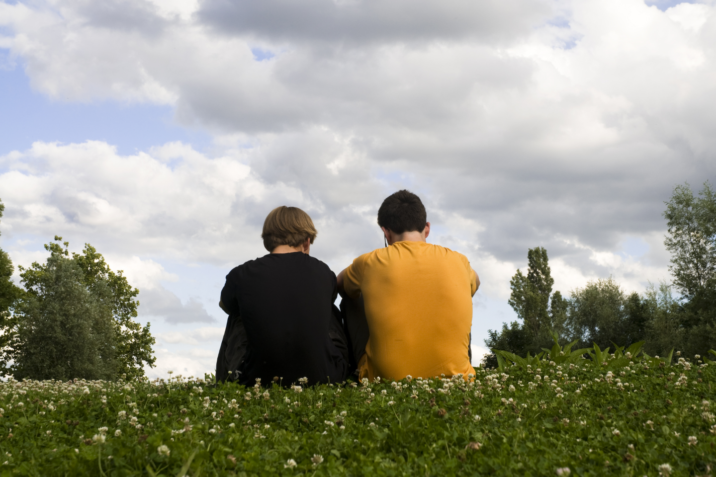 Two teen boys sat on field