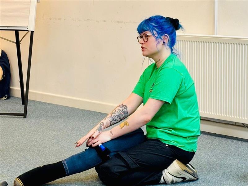 Woman with blue hair and black glasses with dummy leg